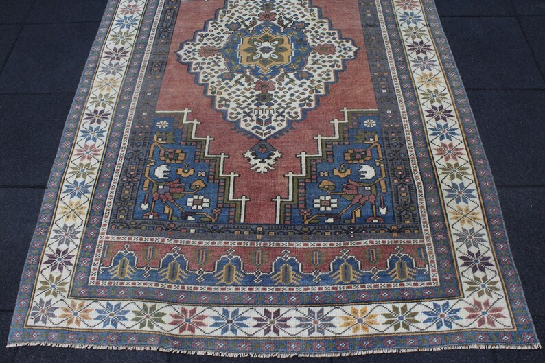 May include: A vintage rug with a red center and blue and white border. The rug has a traditional Persian design with intricate floral patterns.