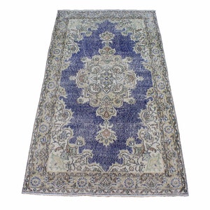 May include: A vintage rug with a blue center and a cream-colored border. The rug has a floral pattern and is in good condition.