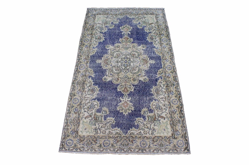 May include: A vintage rug with a blue center and a cream-colored border. The rug has a floral pattern and is in good condition.