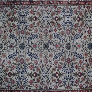 May include: A vintage rug with a cream background and a floral pattern in shades of blue, red, and brown. The rug has a border with a repeating pattern.