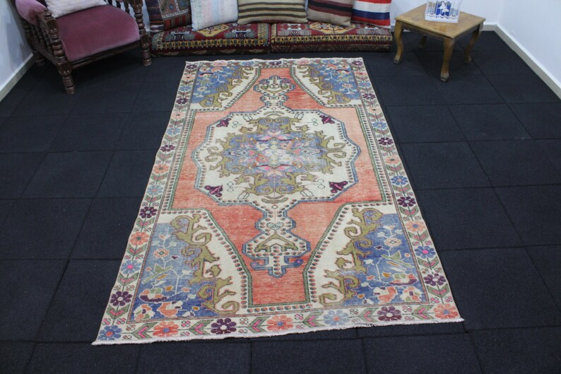 May include: A vintage rug with a floral pattern in shades of pink, blue, and beige. The rug has a central medallion with a geometric design and a border with a repeating floral motif.