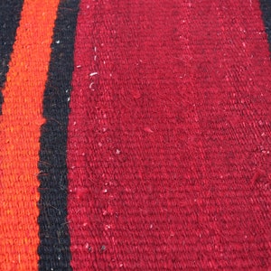 May include: Close-up of a woven fabric with stripes of red, orange, black, and white.