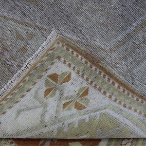 May include: Close-up of the back of a rug with a light brown and white geometric pattern. The rug has a fringe border.