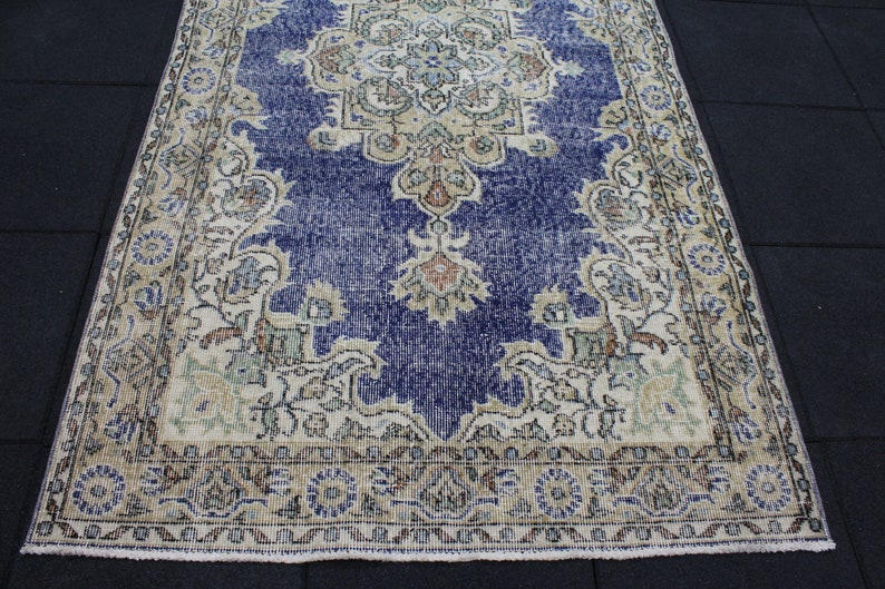 May include: A vintage rug with a blue and cream color scheme. The rug has a floral pattern with a central medallion. The rug is worn and faded, giving it a distressed look.