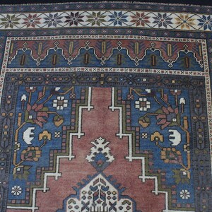 May include: A traditional rug with a blue and red center surrounded by a border of white, green, and brown geometric patterns.