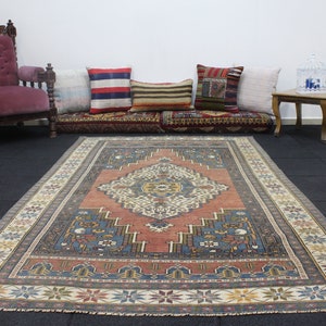 May include: A vintage rug with a traditional Persian design. The rug has a red center with a blue and white geometric pattern. The rug is surrounded by a cream-colored border with a floral design.
