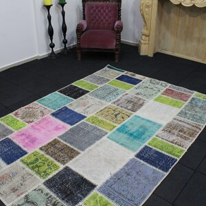May include: A patchwork rug with a variety of colors and patterns. The rug is made up of rectangular patches in shades of pink, blue, green, gray, and cream. The rug is rectangular and appears to be handmade.