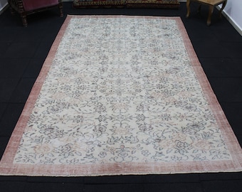 May include: A vintage cream-colored rug with a floral pattern in shades of brown and pink. The rug has a distressed look and a red border.