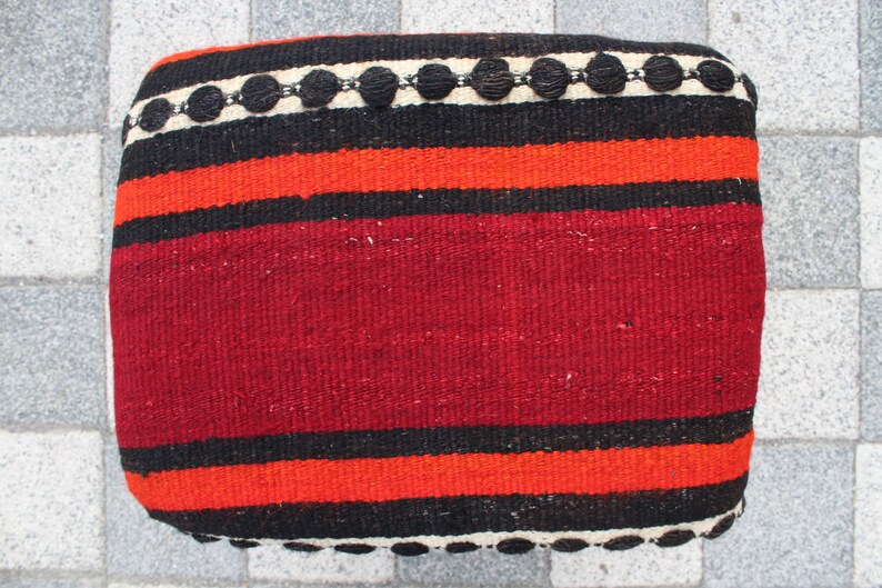 May include: Red, black, and white striped woven cushion with a black and white beaded trim.