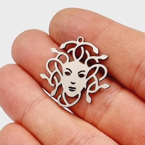 Op de afbeelding: Zilveren bedel met een gedetailleerde uitsnijding van Medusa's gezicht met slangen als haar.
