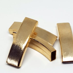 Puede incluir: Cuatro cierres de barra de metal de color dorado, algunos son curvos, otros son rectos.