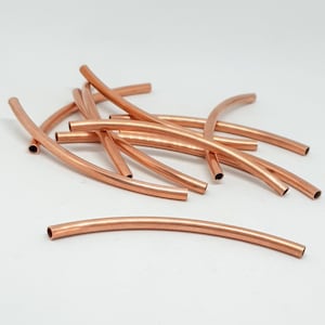 Könnte beinhalten: Eine Gruppe von 10 kupferfarbenen, gebogenen Röhrenperlen. Die Perlen sind etwa 2,5 cm lang und haben eine glatte, polierte Oberfläche.