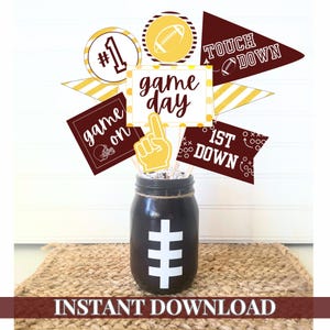 Puede incluir: Un conjunto de decoraciones de fiesta de fútbol imprimibles con una variedad de diseños, que incluyen "game day", "touchdown", "1st down" y una pelota de fútbol con el número "1". Las decoraciones están impresas en cartulina marrón y dorada y son perfectas para una fiesta con temática de fútbol.