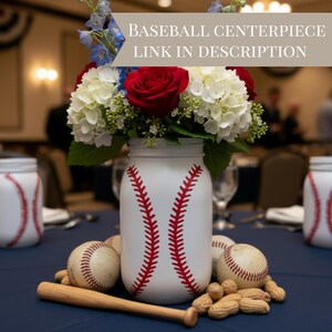K&ouml;nnte beinhalten: Ein Baseball-Themen-Mittelst&uuml;ck mit einem wei&szlig;en Glas mit roten Baseballn&auml;hten, gef&uuml;llt mit wei&szlig;en Hortensien, roten Rosen und blauen Blumen. Baseb&auml;lle, Erdn&uuml;sse und ein kleiner Holzschl&auml;ger vervollst&auml;ndigen das Arrangement. Text: BASEBALL CENTERPIECE LINK IN DESCRIPTION.