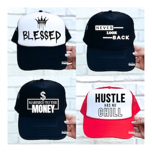 Puede incluir: Cuatro gorras de camionero con diferentes diseños. La primera gorra es blanca con texto negro que dice "BLESSED" y una corona con pintura goteando. La segunda gorra es negra con texto blanco que dice "NEVER LOOK BACK". La tercera gorra es negra con texto blanco que dice "MARRIED TO THE MONEY" y un signo de dólar. La cuarta gorra es roja con texto blanco que dice "HUSTLE HAS NO CHILL".