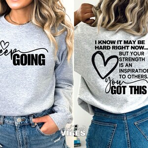 May include: Gray sweatshirt with black text that reads "Keep Going" on the front and "I know it may be hard right now... But your strength is an inspiration to others. You got this" on the back.