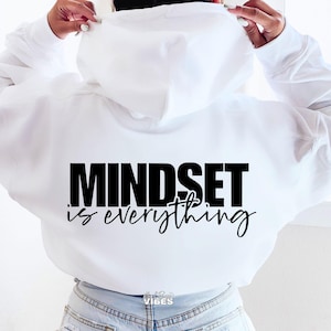 May include: White hoodie with black text that reads "Mindset is everything" on the back.
