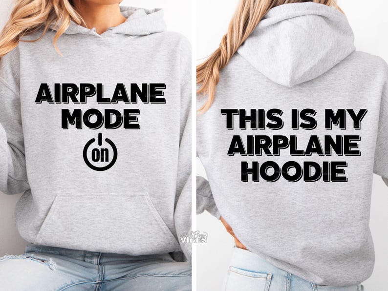 Puede incluir: Una sudadera con capucha gris claro con las palabras "AIRPLANE MODE" encima de un s&iacute;mbolo de bot&oacute;n de encendido con "on" dentro. La parte trasera de la sudadera con capucha dice "THIS IS MY AIRPLANE HOODIE" en letras negras. La sudadera tiene un bolsillo delantero y una capucha.