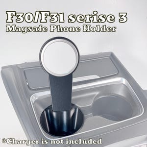 Può includere: Un supporto per telefono MagSafe nero progettato per veicoli serie 3 F30/F31, dotato di un attacco magnetico circolare su un supporto verticale che si inserisce in un portabicchieri. Il testo F30/F31 serise 3 Magsafe Phone Holder è visibile.