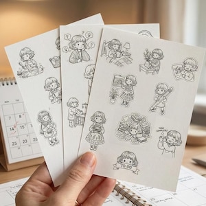 May include: Three sheets of stickers featuring black and white illustrations of a girl in various activities. The stickers depict scenes like reading, writing, and organizing. A calendar and notebook are visible in the background.