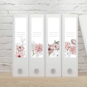 Puede incluir: Cuatro archivadores blancos con diseños florales. Cada archivador tiene una etiqueta blanca vertical con una ilustración de acuarela de peonías rosas y hojas. Las etiquetas también incluyen tres líneas horizontales.