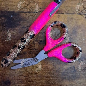 May include: A pink and gold glitter pen and a pink and gold glitter pair of scissors with black leopard print accents.