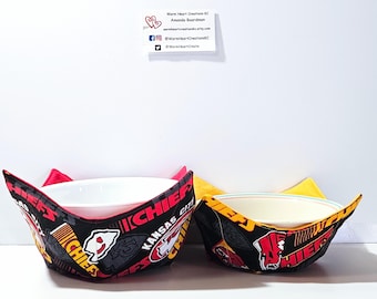May include: Two fabric bowl cozies in black, red, and yellow with the Kansas City Chiefs logo and text. The larger cozy is red and the smaller cozy is yellow.