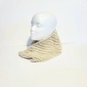May include: A beige knitted infinity scarf, worn on a white mannequin head.