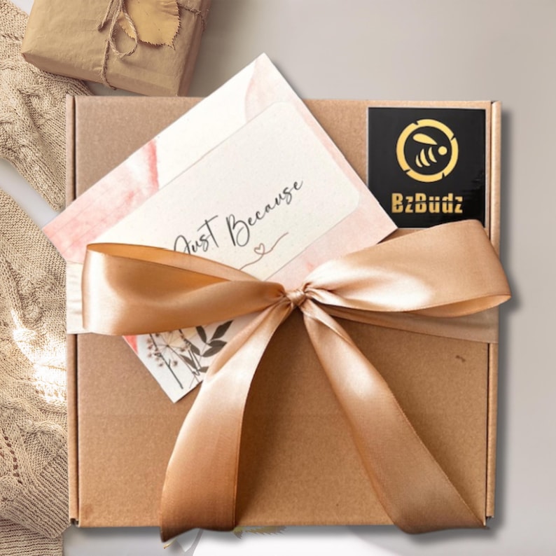 May include: A brown cardboard box tied with a gold ribbon and a card that says "Just Because". The box has a black sticker with a bee logo and the text "BzBuddz".