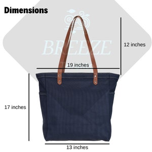 K&ouml;nnte beinhalten: Eine dunkelblaue Canvas-Tragetasche mit braunen Ledergriffen und einem wei&szlig;en gestickten Design. Die Tasche misst 48 cm in der Breite, 43 cm in der H&ouml;he und 33 cm in der Tiefe.