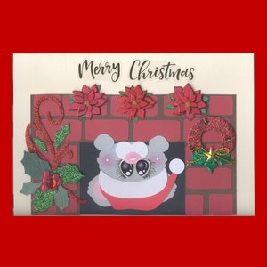 May include: A Christmas card with a gray and white cartoon mouse peeking out of a fireplace. The fireplace is made of red and brown bricks with green holly and red poinsettia decorations. The card says "Merry Christmas" at the top.