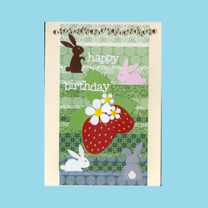 May include: A handmade birthday card with a strawberry and bunny theme. The card features a red strawberry with white flowers, green leaves, and several bunny cutouts in brown, pink, white, and gray. The words "happy birthday" are written in white.