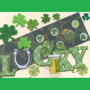 May include: A green and white card with the word "LUCKY" in large letters. The letters are decorated with a plaid pattern. The card is decorated with shamrocks, a horseshoe, and a beer mug.