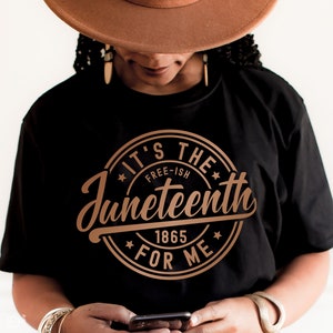 May include: A black t-shirt with a gold circle graphic that says "It's the Free-ish Juneteenth 1865 For Me".
