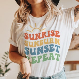 Könnte beinhalten: Weißes T-Shirt mit einer Retro-Grafik, auf der "Sunrise Sunburn Sunset Repeat" in Regenbogenfarben steht.