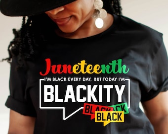 May include: A black t-shirt with a graphic design that says "Juneteenth I'm Black Every Day, But Today I'm Blackity" with a speech bubble and three banners that say "Black" in red, green, and yellow.