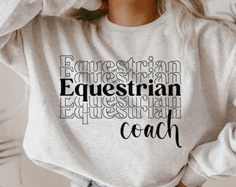 May include: A gray sweatshirt with the text "Equestrian" repeated in a stacked, layered design. The text "coach" is written in cursive below the stacked text.