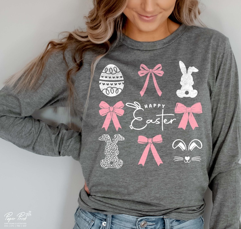 May include: A gray long-sleeved shirt with a white graphic design featuring pink bows, bunnies, and an Easter egg. The text "Happy Easter" is also included in the design.