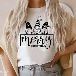K&ouml;nnte beinhalten: Wei&szlig;es T-Shirt mit einer schwarzen Grafik von drei Gnomen, die H&uuml;te tragen, und dem Text "merry christmas".