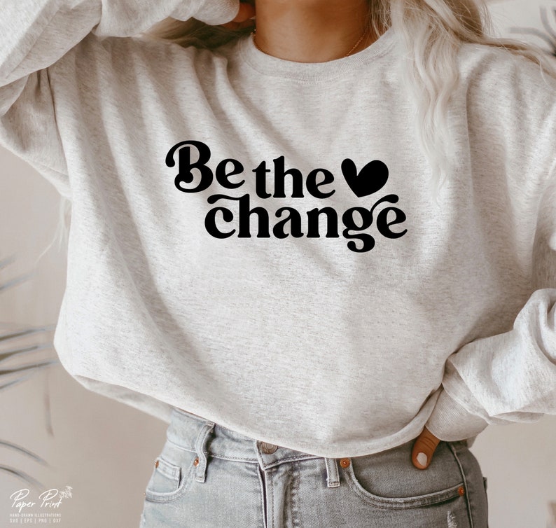 Puede incluir: Una sudadera gris con el texto "Be the change" en negro con un s&iacute;mbolo de coraz&oacute;n.
