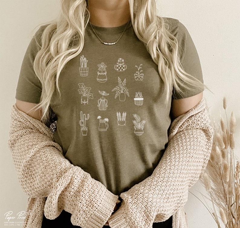 May include: A green t-shirt with a white outline of various potted plants. The shirt has a crew neck and short sleeves.