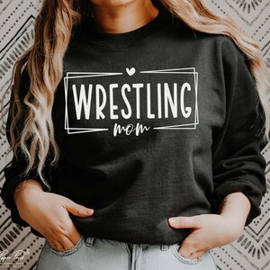 May include: Black sweatshirt with white text that says "WRESTLING mom" in a box with a small heart above the text.