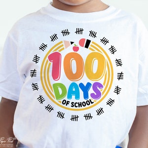 May include: White t-shirt with a colorful graphic that says "100 Days of School". The graphic is surrounded by a circle of black hash marks.