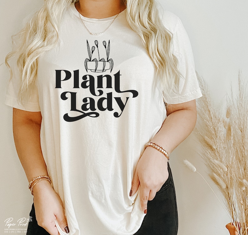 May include: A white t-shirt with a black graphic of a potted plant and the text "Plant Lady" in a retro font.