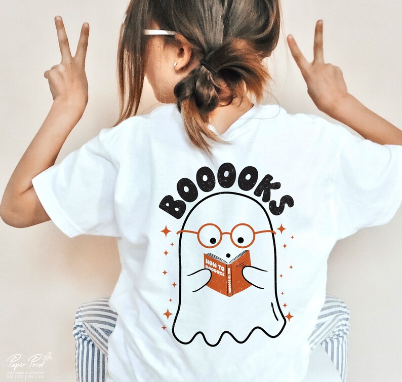 Pode incluir: Camiseta branca com um fantasma usando &oacute;culos e lendo um livro que diz "How to Boooks". O texto acima do fantasma diz "Booooks".