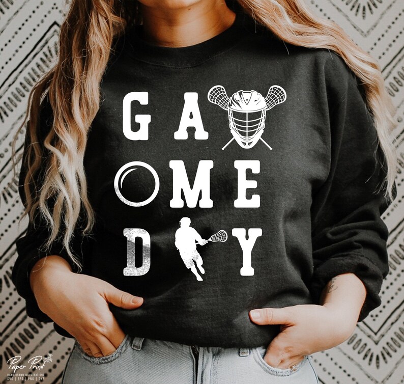 May include: Black sweatshirt with white text that reads "Game Day" with a lacrosse stick and helmet graphic.