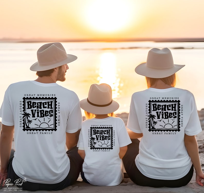 Puede incluir: Una familia de tres personas con camisetas blancas con un dise&ntilde;o de sello negro que dice "Beach Vibes" y el texto "Great Memories, Great Laughs, Great Times, Great Family". La familia est&aacute; sentada en una playa al atardecer.