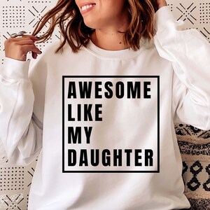May include: White sweatshirt with black text that reads "AWESOME LIKE MY DAUGHTER" in a box.