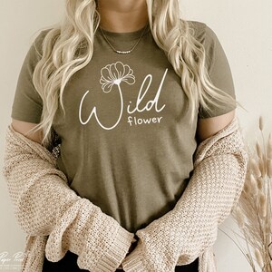 May include: A green t-shirt with a white graphic of a flower and the text "Wild flower".