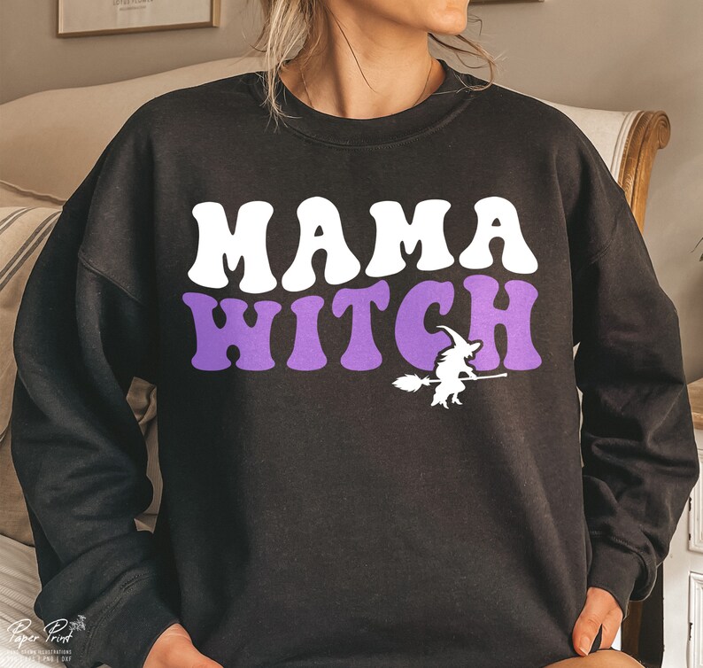 Pu&ograve; includere: Felpa nera con il testo "MAMA WITCH" in lettere bianche e viola. Sotto il testo c'&egrave; una piccola silhouette di una strega che vola su una scopa.